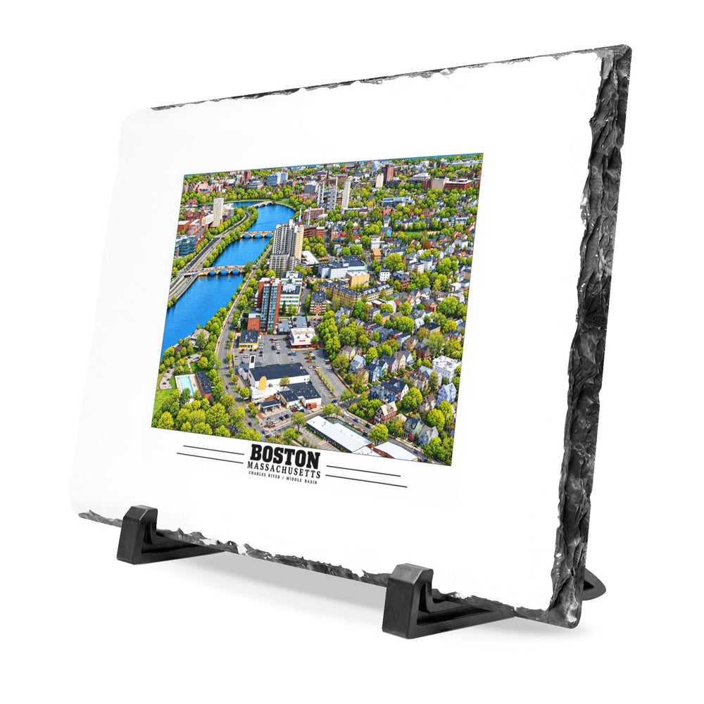 Angled rough-edged slate display on black stands showing Charles River aerial city view with bridges, buildings and green trees artwork