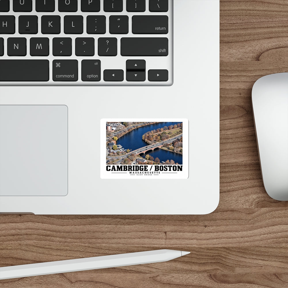 Sticker showing Eliot Bridge aerial river view artwork on a laptop beside its keyboard