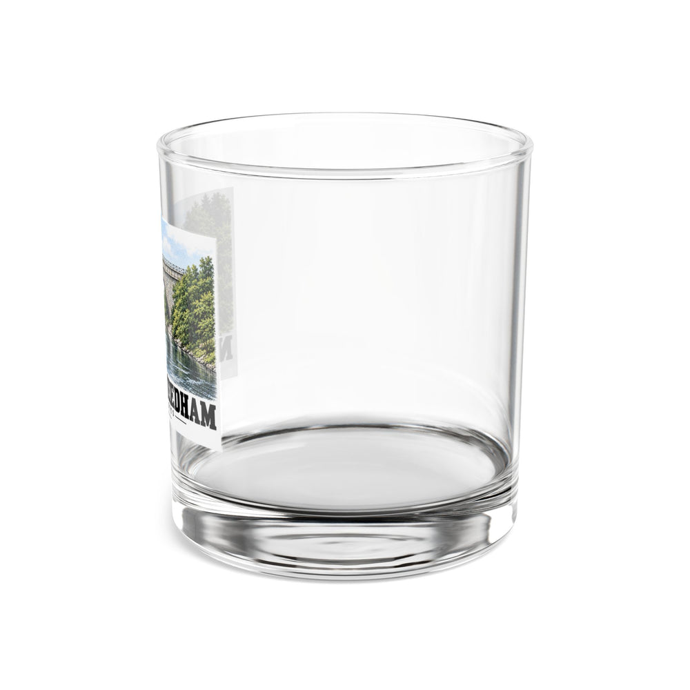 Side view of a clear rocks glass with part of the Echo Bridge artwork showing a stone arch over a river and trees, with Newton/Needham lettering visible on the left.