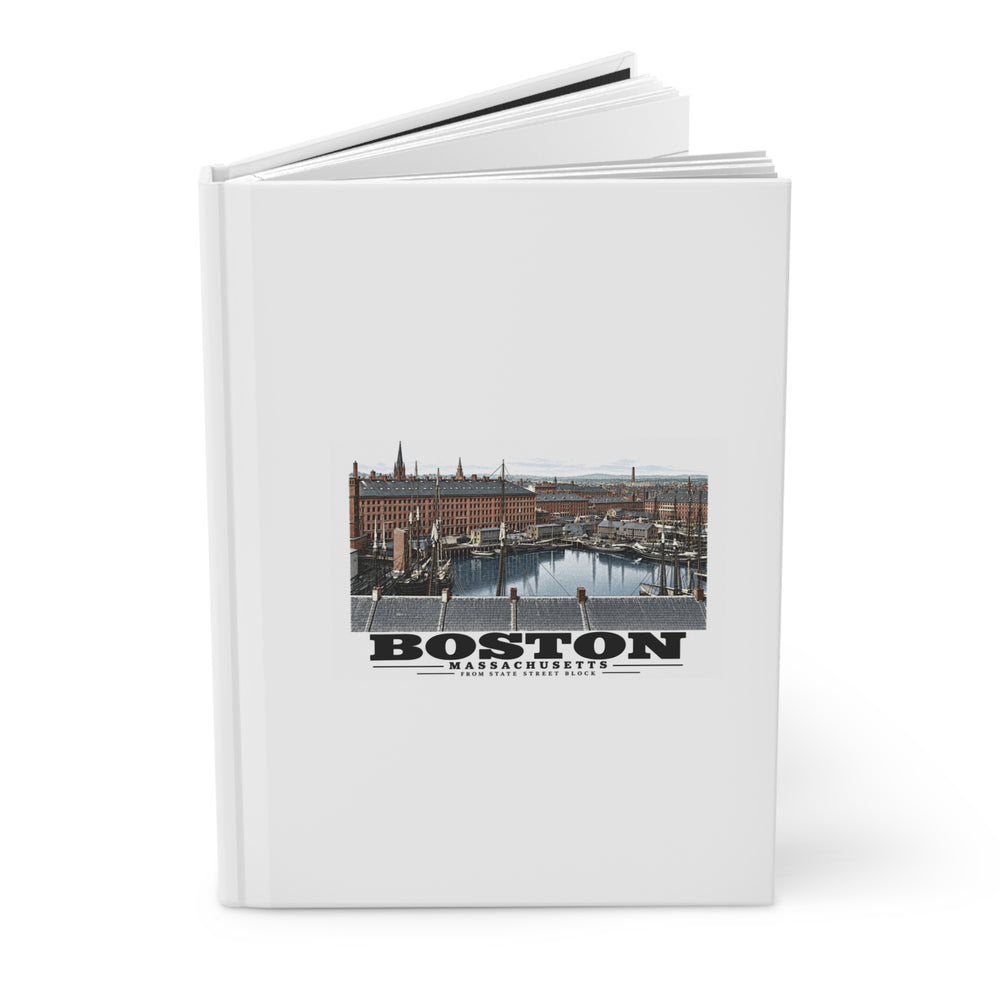 Partly opened white hardcover journal showing Boston waterfront buildings, wharves, boats and harbor water artwork on the front