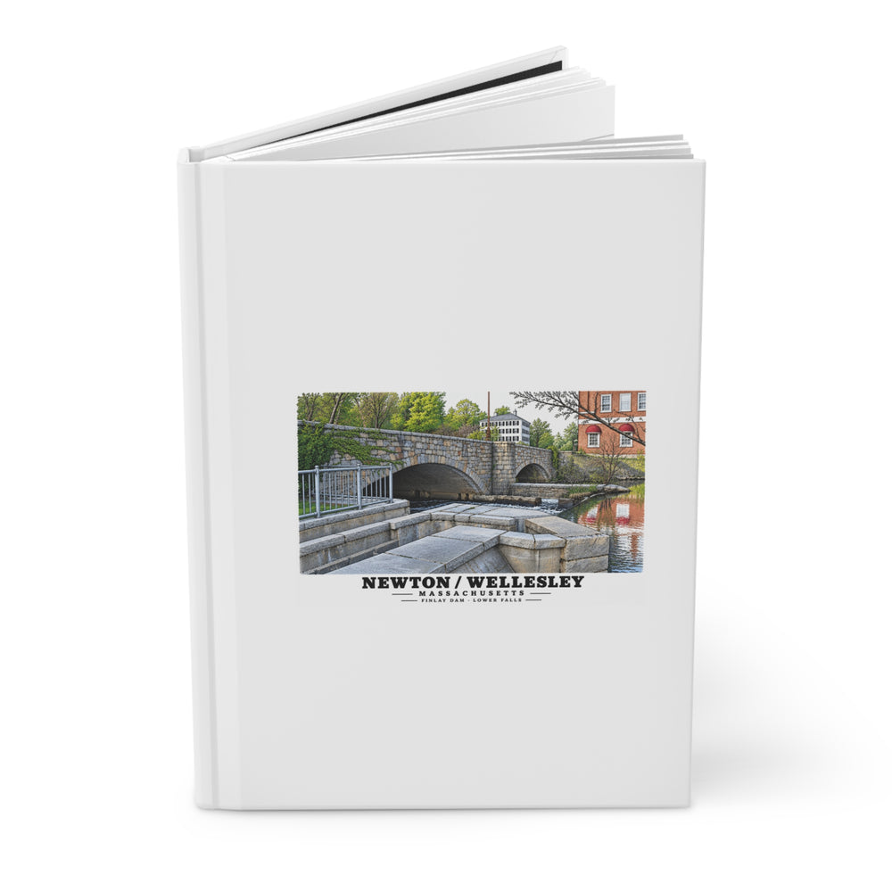 Partly opened white hardcover journal showing Finlay Dam stone arches and water artwork on the front