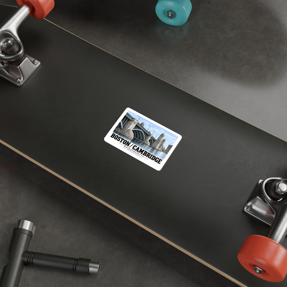 Sticker showing Longfellow Bridge piers and towers with Boston/Cambridge lettering on the underside of a black skateboard with metal trucks and colored wheels