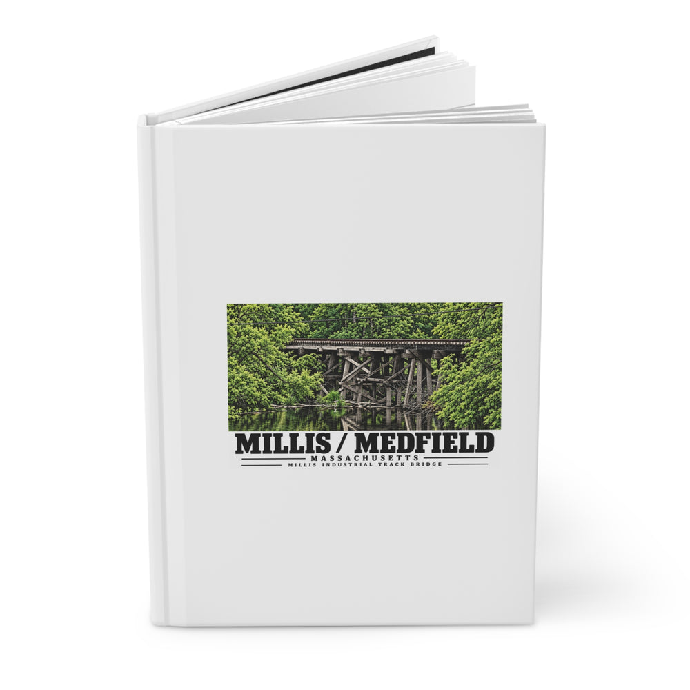 Partly opened white hardcover journal showing Millis Industrial Track wooden railway trestle and green foliage artwork on the front
