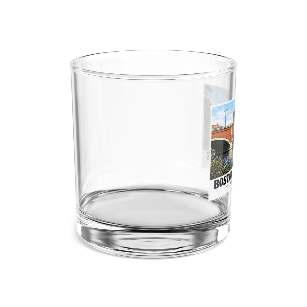 Side view of clear rocks glass with mostly unprinted surface and part of Eliot Bridge red brick arches and boats print at right