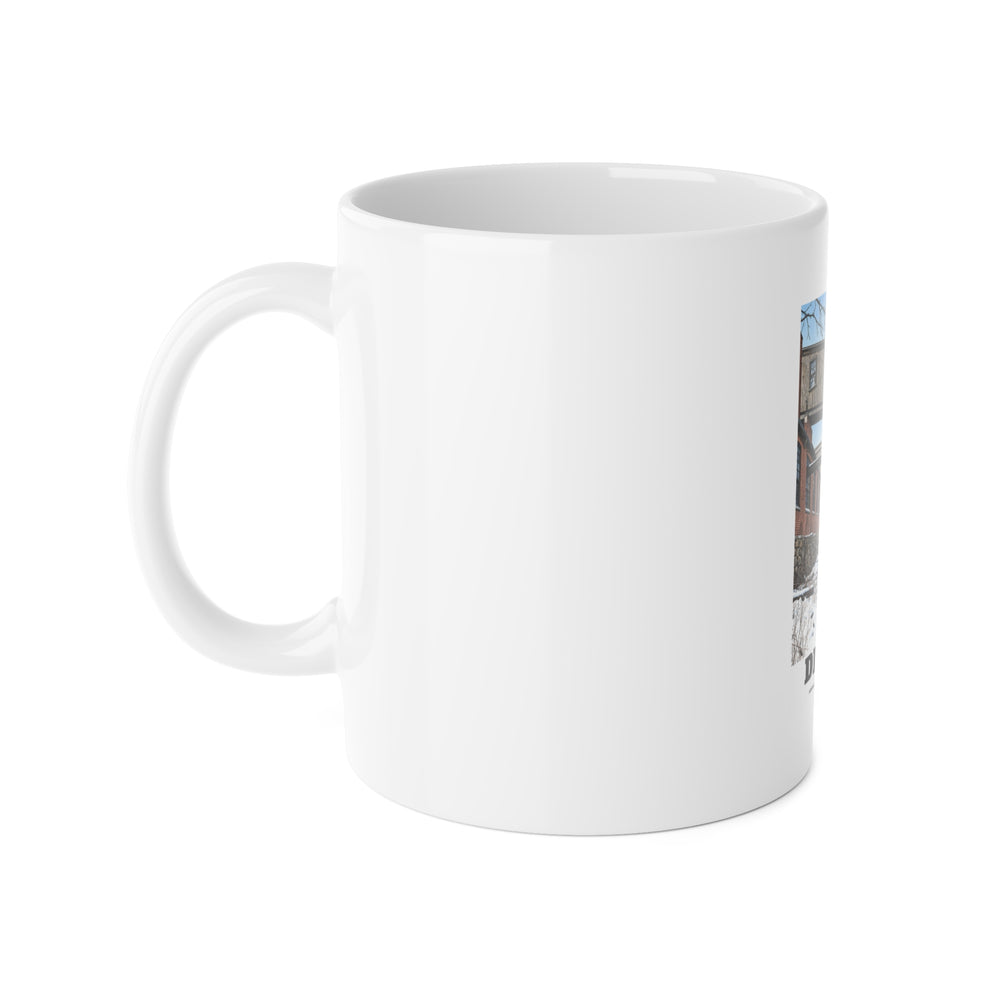 Left handle-side view of 11 oz white ceramic mug, with Norfolk Manufacturing Company Cotton Mill artwork partly visible.