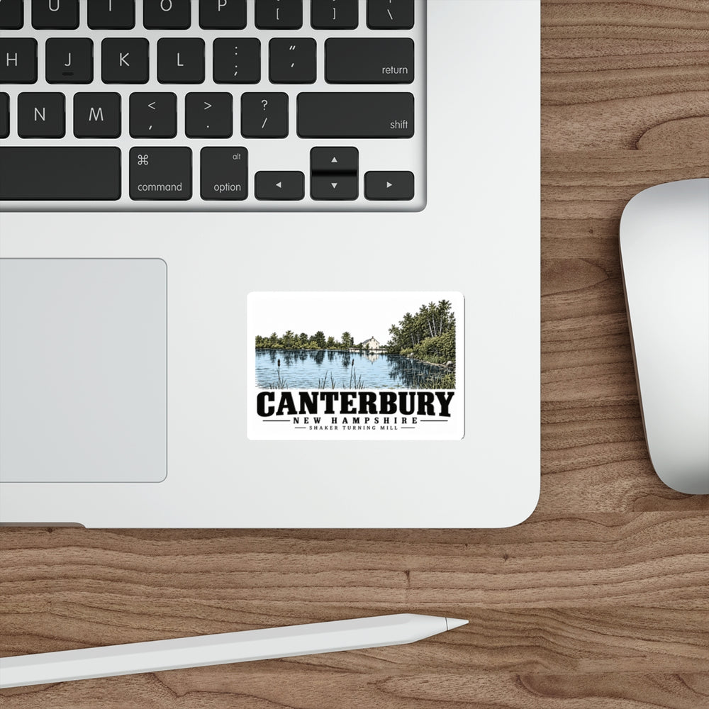 Laptop display of Shaker turning mill and pond white die-cut sticker, with Canterbury, New Hampshire artwork and lettering.