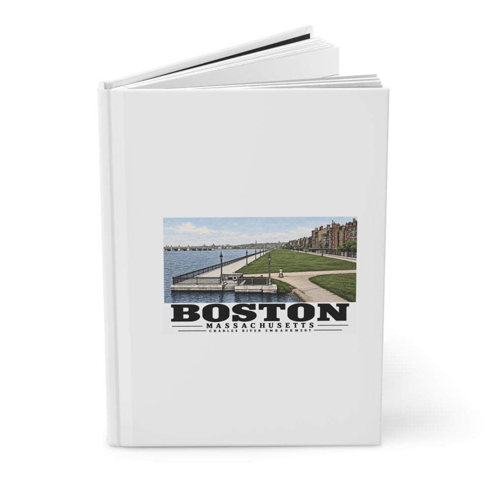 Partly opened white hardcover journal showing Charles River Embankment riverside path, lawn and buildings artwork on the front