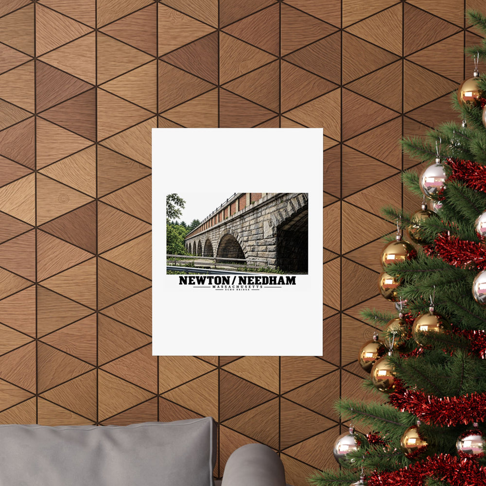 Poster with Echo Bridge artwork showing a row of stone arches and a brick upper band, with Newton/Needham lettering displayed on a wood-patterned wall beside a decorated evergreen.