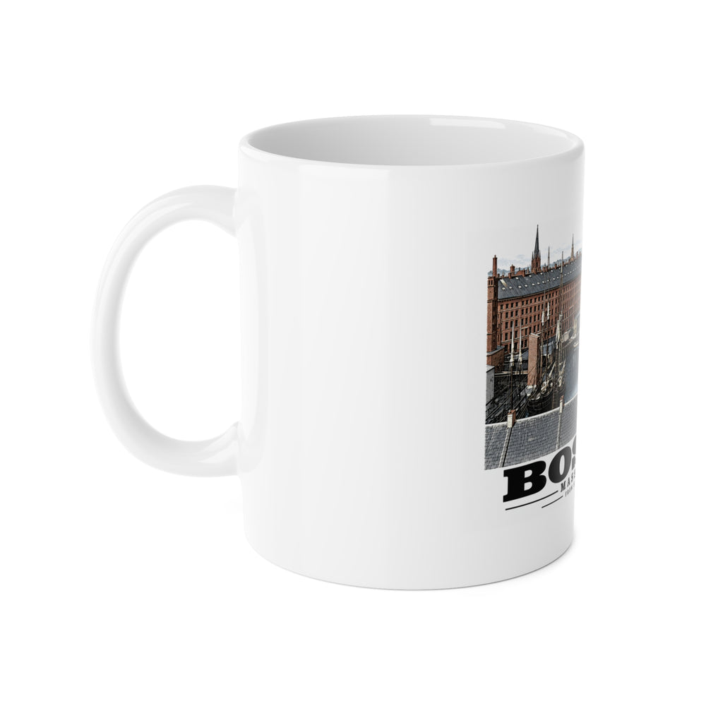 White mug with handle at left and part of the Boston waterfront buildings, wharves, boats and harbor water print at right