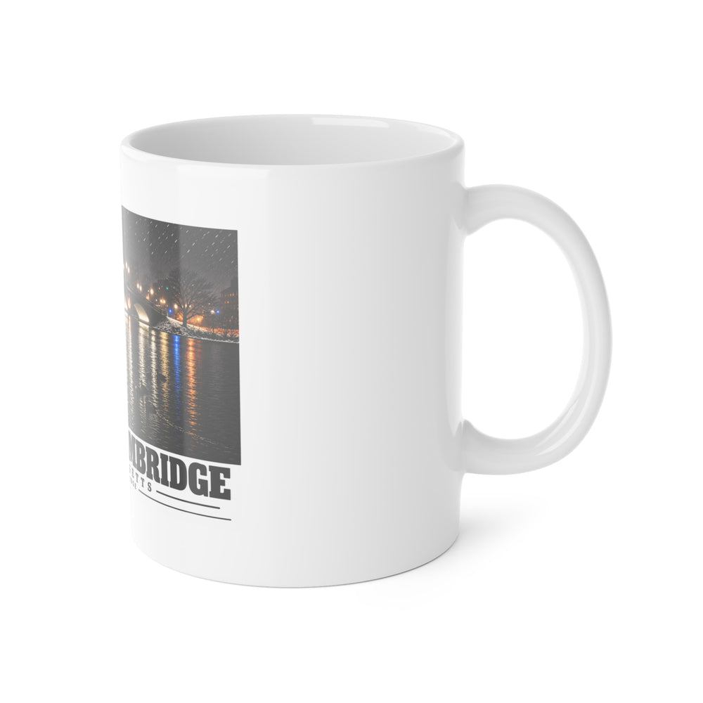 White mug with handle at right and part of the Weeks Footbridge illuminated night view with water reflections print at left