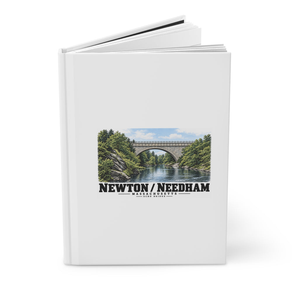 Partly opened white hardcover journal with Echo Bridge artwork showing a stone arch over a river and trees, with Newton/Needham lettering on its front cover.