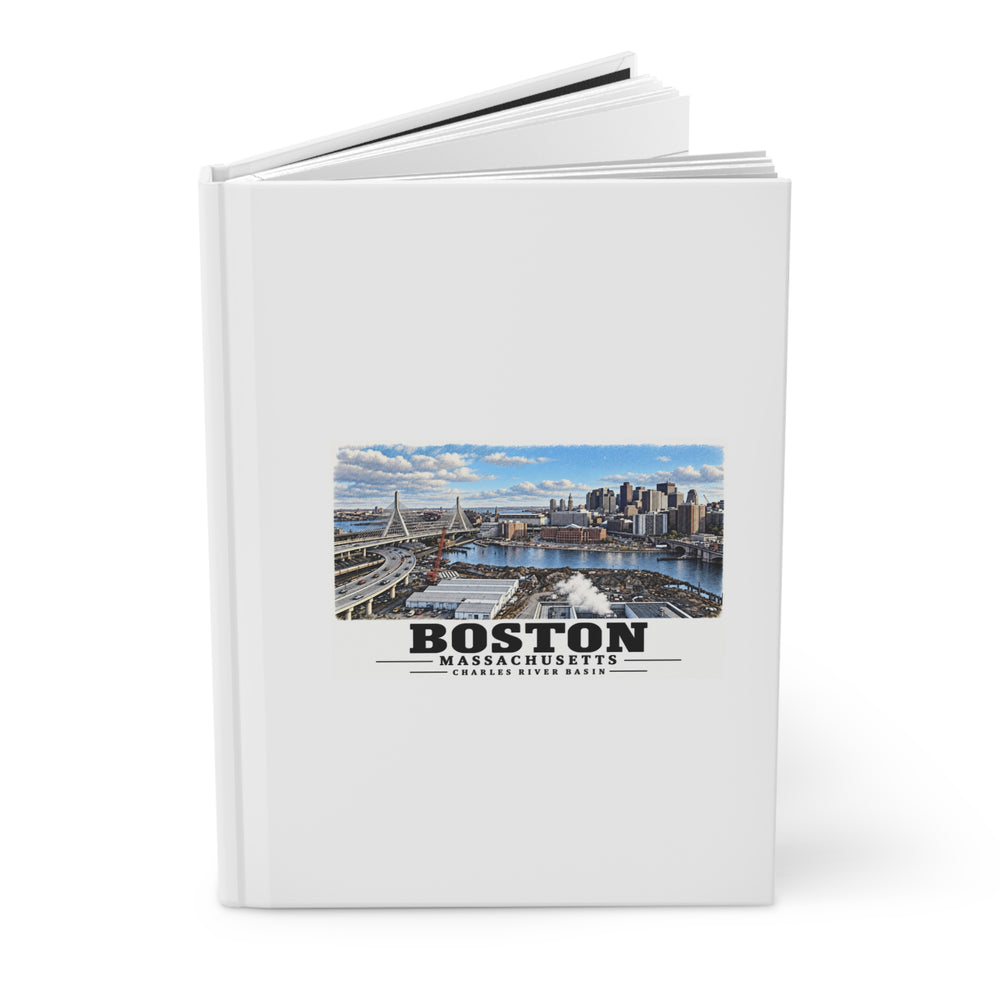 Partly opened white hardcover journal showing Boston skyline, cable-stayed bridge and Charles River basin artwork on the front