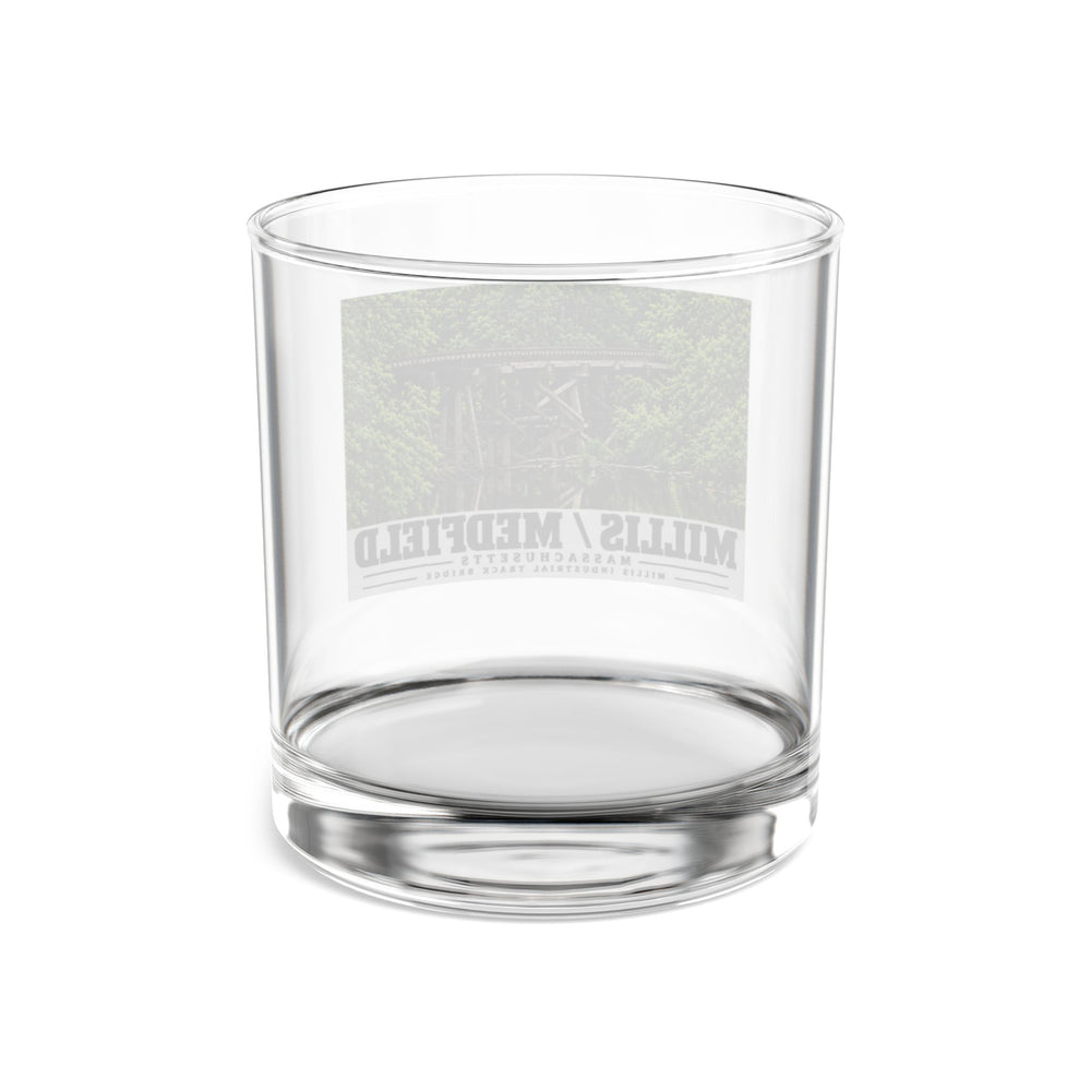 Rear view of clear rocks glass with Millis Industrial Track wooden railway trestle and green foliage print and reversed lettering visible through the glass