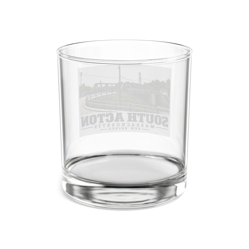 Rear view through clear New Bridge 10 oz rocks glass, with the South Acton bridge artwork faintly visible in reverse.