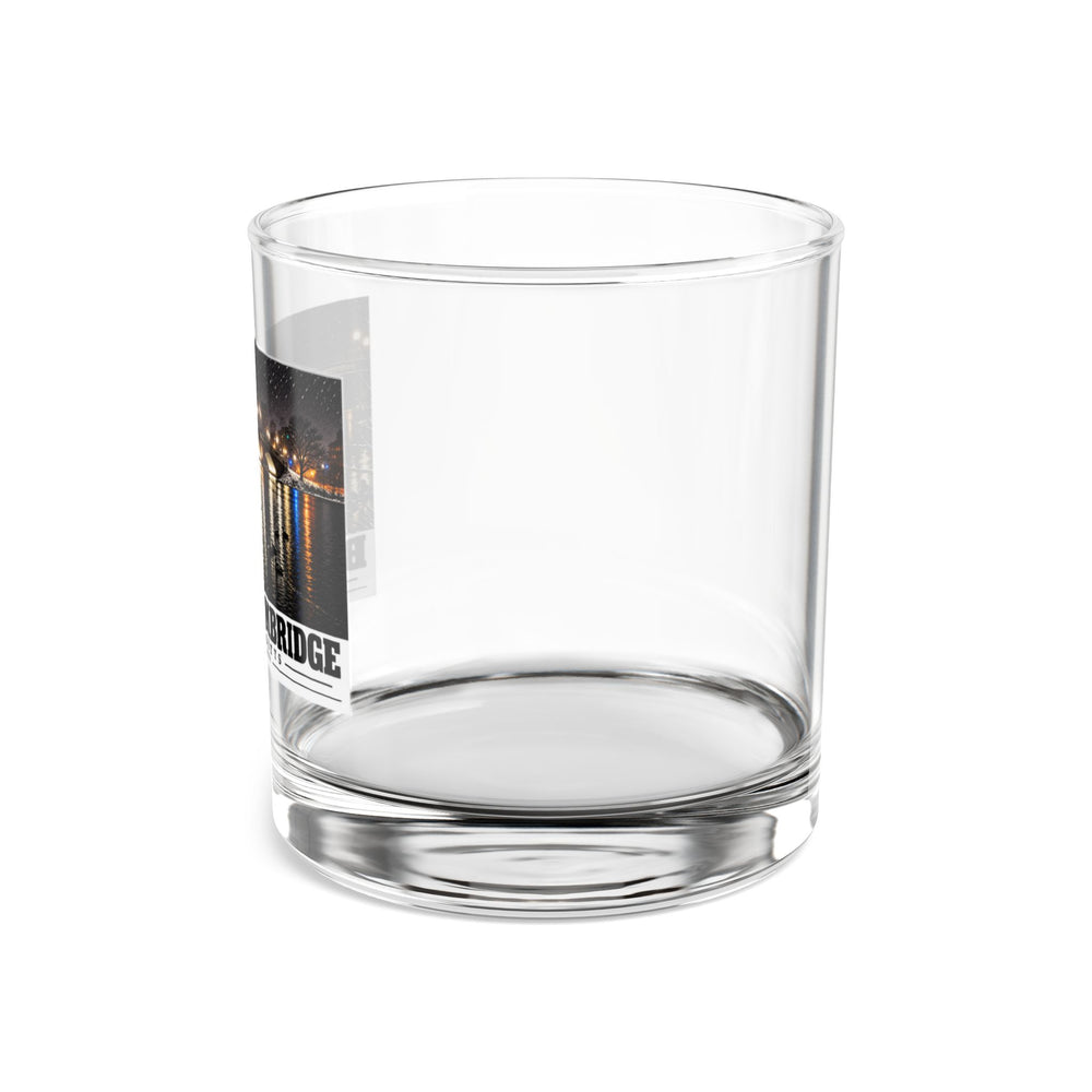 Side view of clear rocks glass with mostly unprinted surface and part of Weeks Footbridge illuminated night view with water reflections print at left