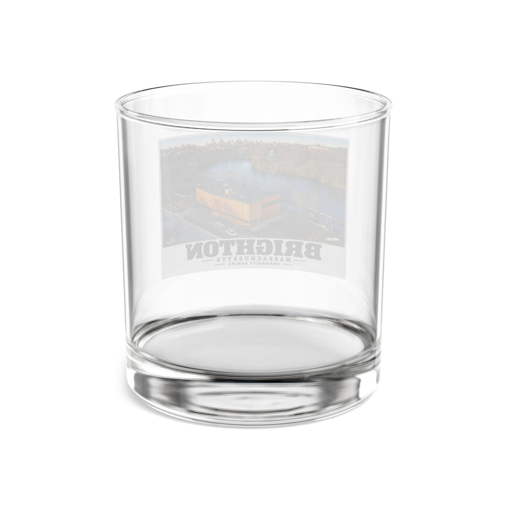 Rear view of clear rocks glass with Community Rowing aerial building and river print and reversed lettering visible through the glass