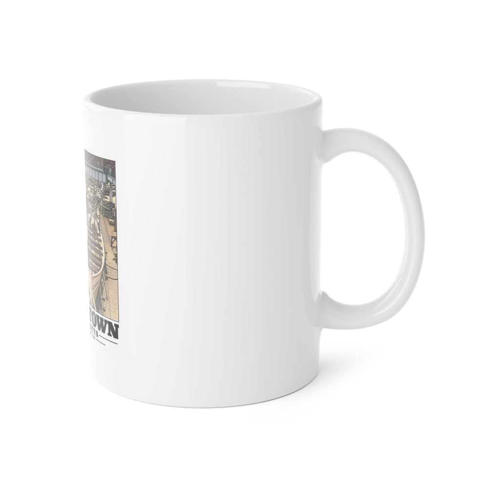 Right side of ceramic mug showing handle and edge of small-boat building artwork