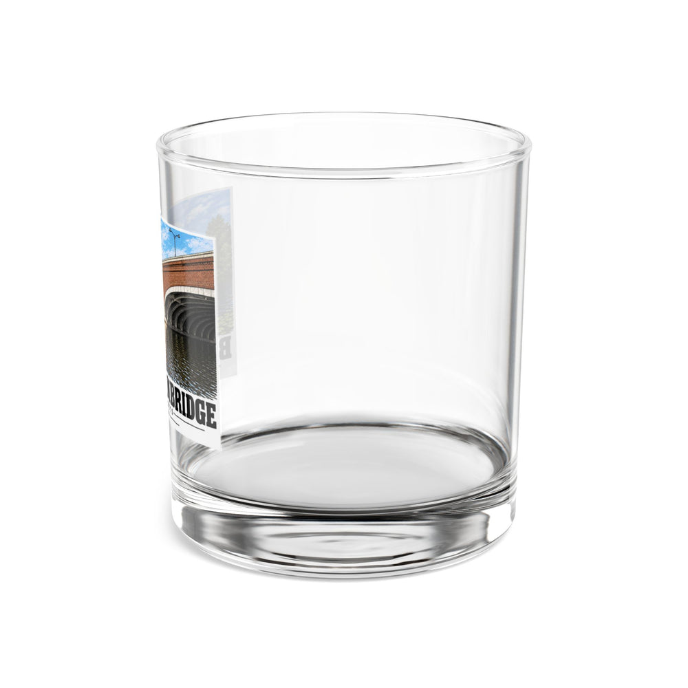 Side view of clear rocks glass with mostly unprinted surface and part of Eliot Bridge close red brick arch view print at left
