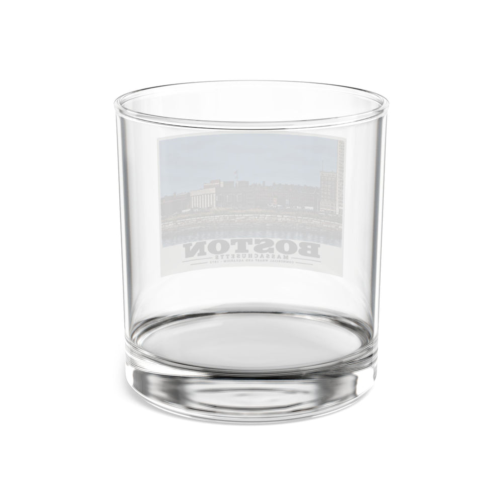 Rear view of clear rocks glass with Commercial Wharf and Aquarium waterfront buildings, stone seawall and harbor water print and reversed lettering visible through the glass