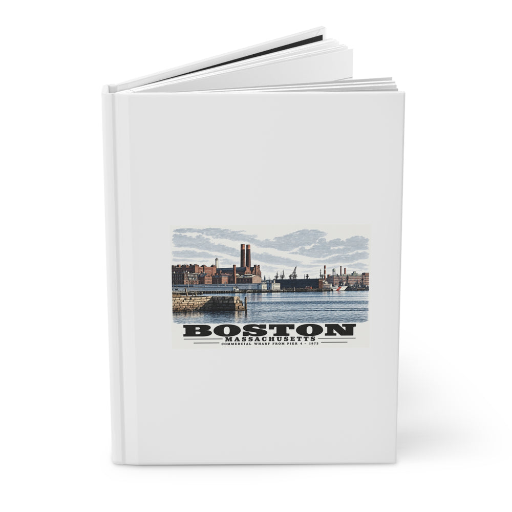 Partly opened white hardcover journal showing Commercial Wharf waterfront buildings, twin chimneys and harbor water artwork on the front