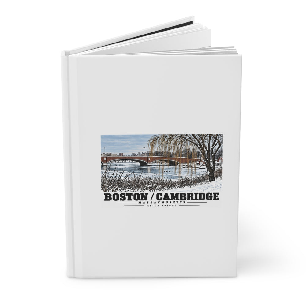 Partly opened white hardcover journal showing Eliot Bridge winter river view with snow and bare trees artwork on the front