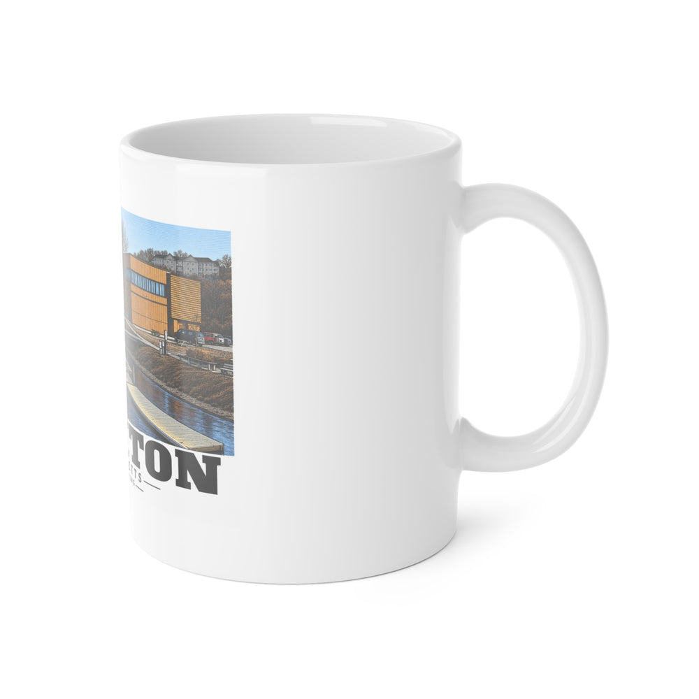 White mug with handle at right and part of the Community Rowing building, dock and boats print at left