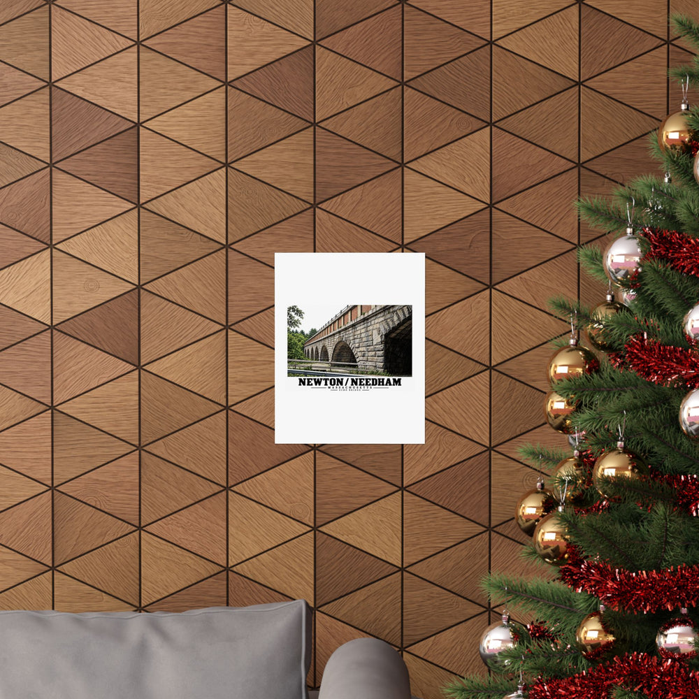 Poster with Echo Bridge artwork showing a row of stone arches and a brick upper band, with Newton/Needham lettering displayed on a wood-patterned wall beside a decorated evergreen.