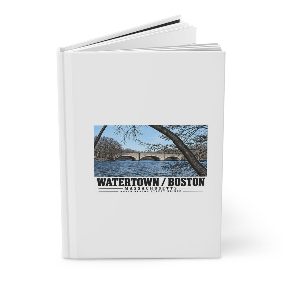 Partly opened white hardcover journal showing North Beacon Street Bridge stone arches framed by a bare tree artwork on the front