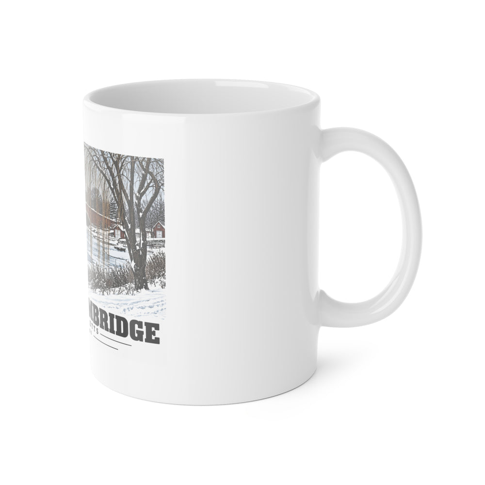 White mug with handle at right and part of the Eliot Bridge winter river view with snow and bare trees print at left