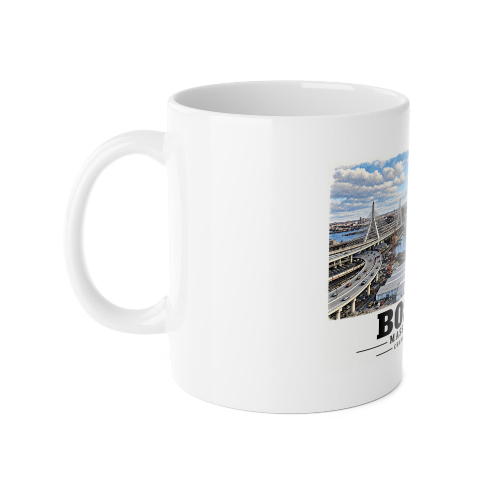 White mug with handle at left and part of the Boston skyline, cable-stayed bridge and Charles River basin print at right