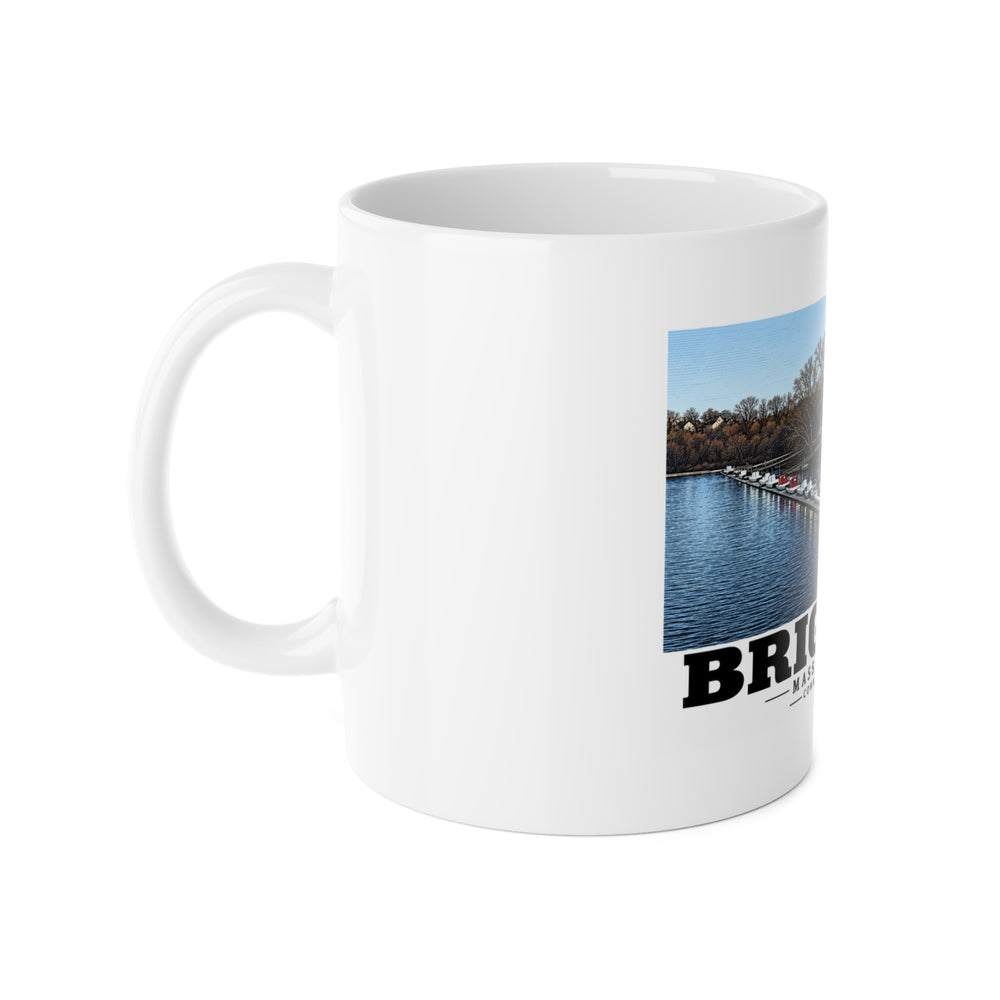 White mug with handle at left and part of the Community Rowing building, dock and boats print at right
