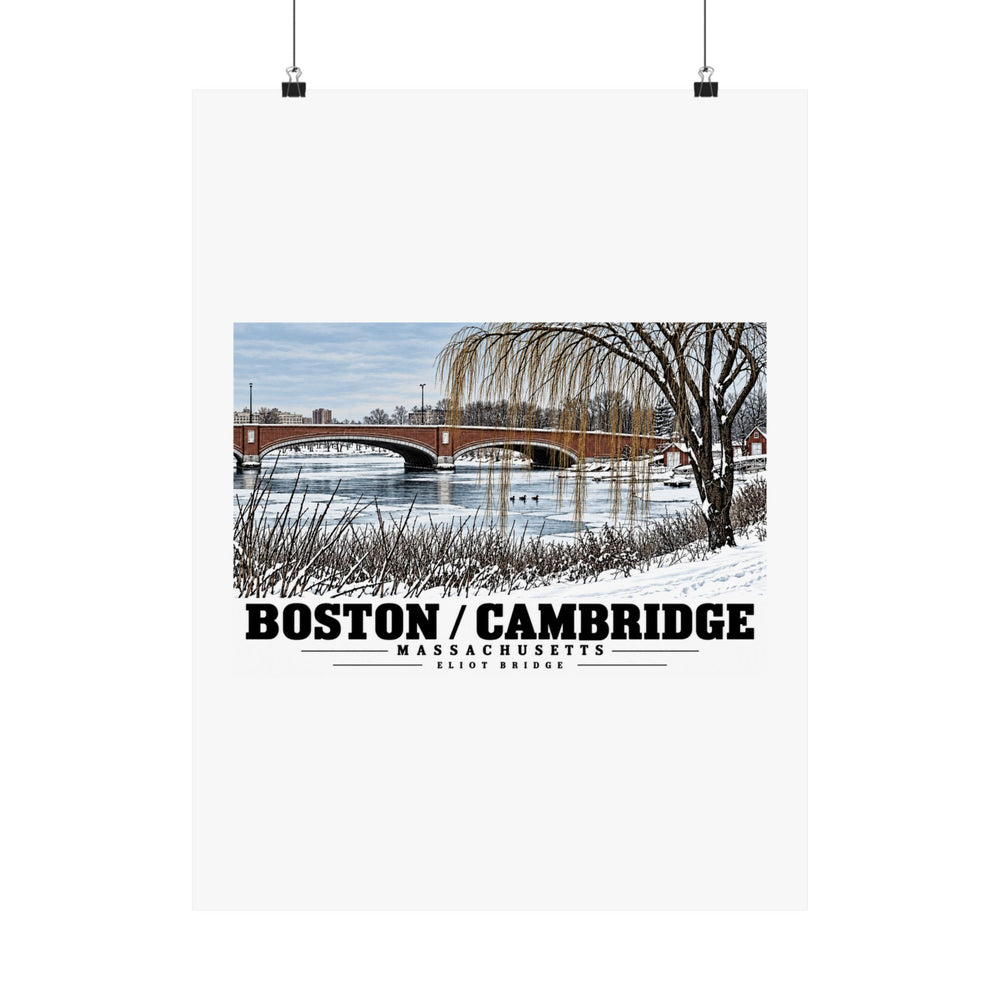 Eliot Bridge winter river view with snow and bare trees poster with Boston/Cambridge lettering hanging from two binder clips