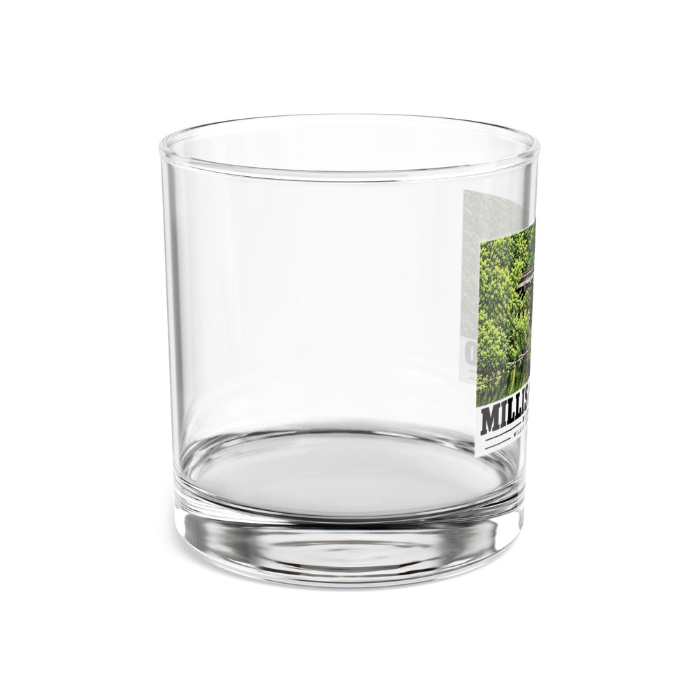 Side view of clear rocks glass with mostly unprinted surface and part of Millis Industrial Track wooden railway trestle and green foliage print at right