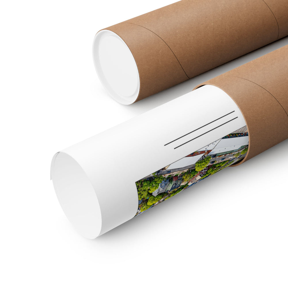 Partly rolled poster extending from a cardboard tube with a narrow strip of the aerial city artwork and horizontal label lines visible; place lettering obscured