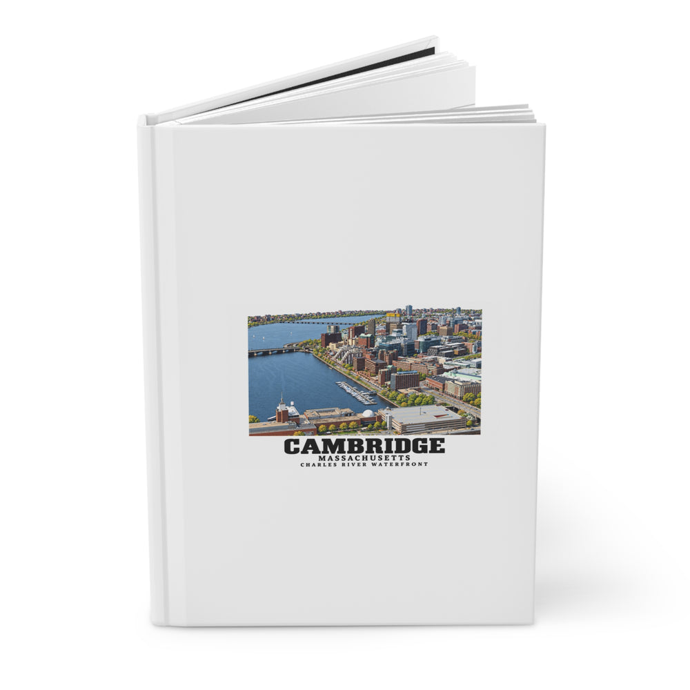 Partly opened white hardcover journal showing Cambridge Charles River waterfront aerial city view artwork on the front