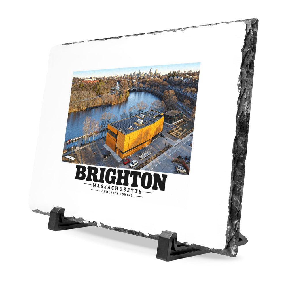 Angled rough-edged slate display on black stands showing Community Rowing aerial building and river artwork