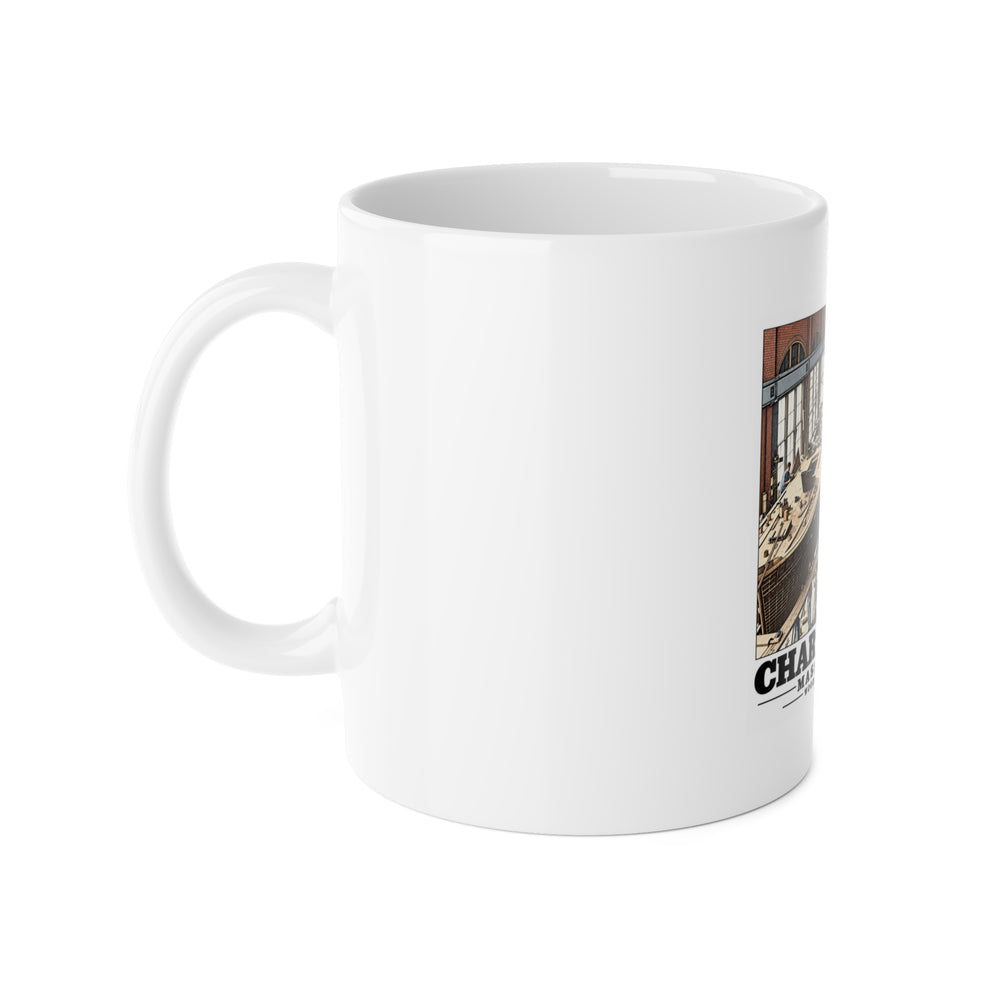 Left side of white ceramic mug showing handle and partial small-boat building artwork
