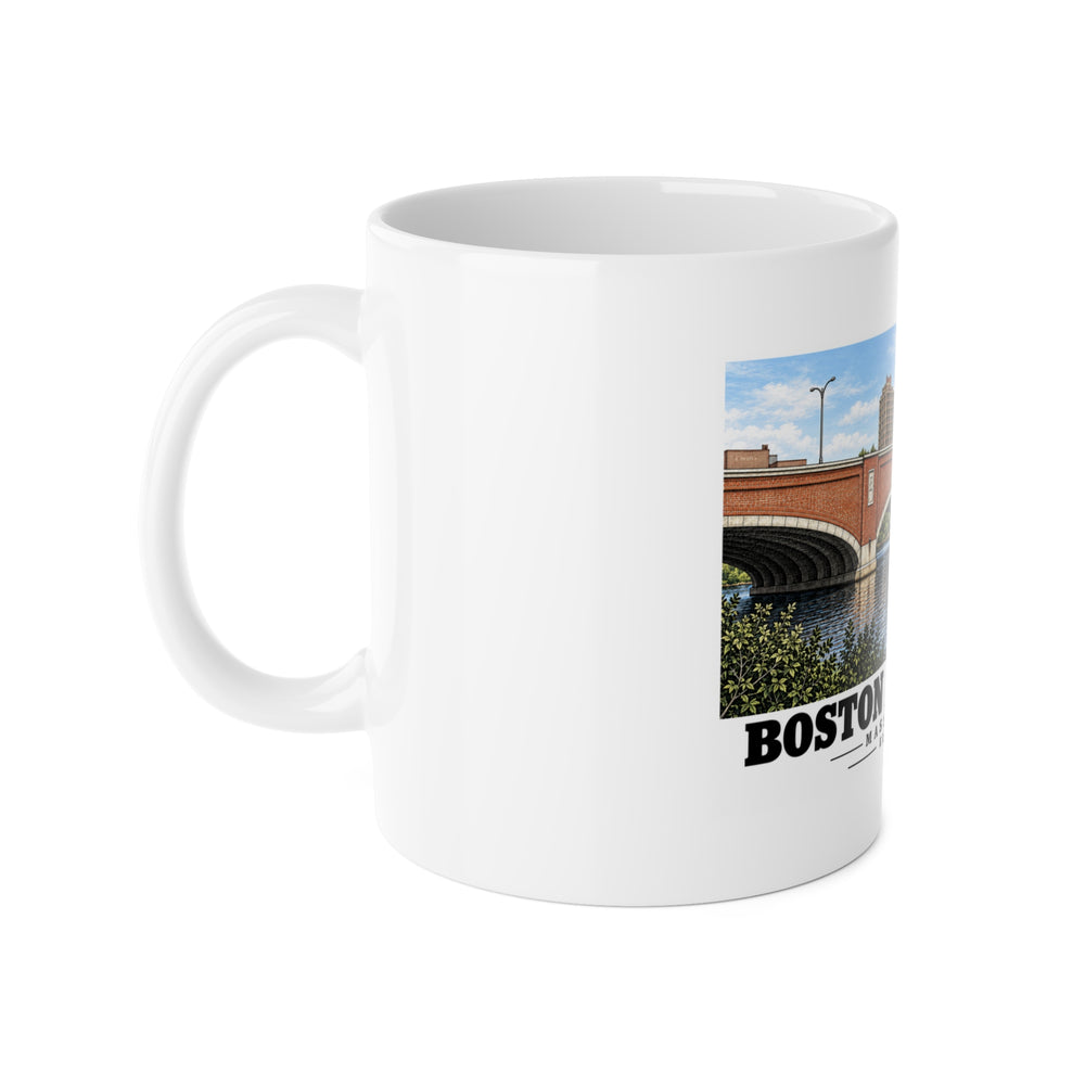 White mug with handle at left and part of the Eliot Bridge red brick arches and boats print at right