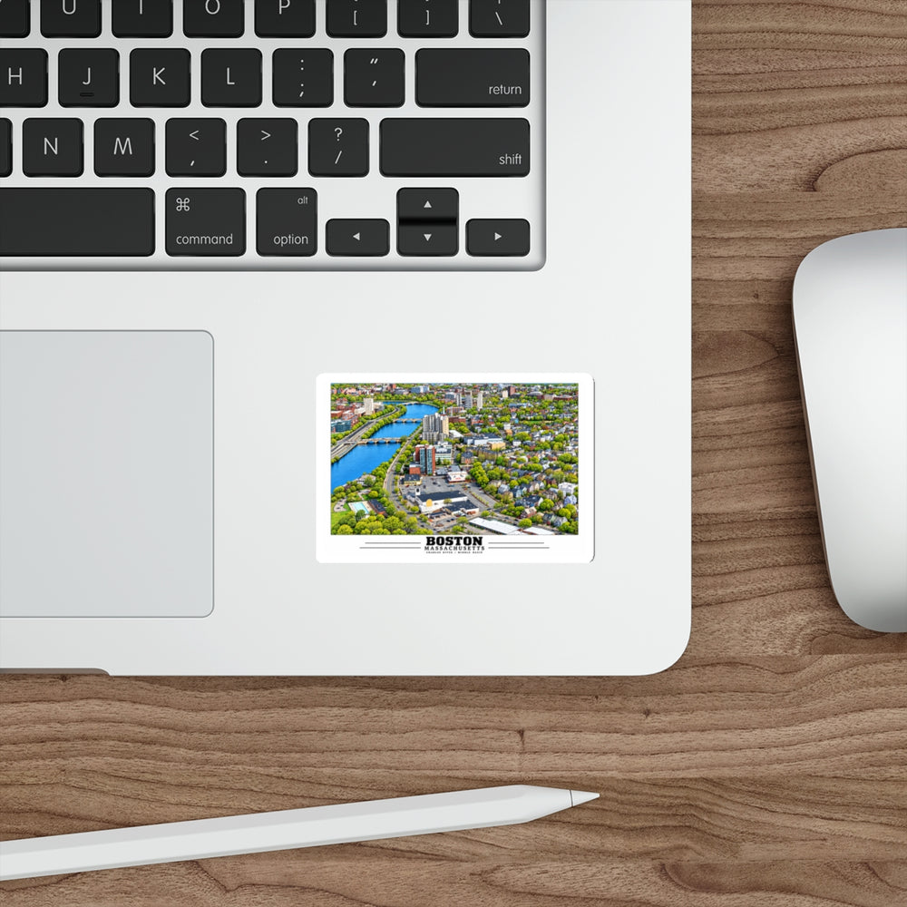Sticker showing Charles River aerial city view with bridges, buildings and green trees artwork on a laptop beside its keyboard
