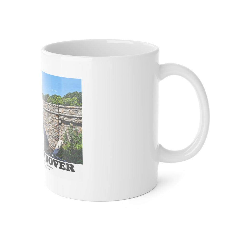 White mug with handle at right and part of the South Street Bridge stone arch and river print at left