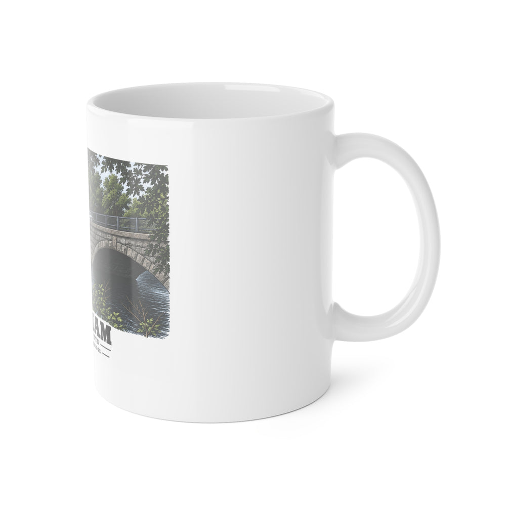 White mug with handle at right and part of the Prospect Street Bridge stone arches and river print at left