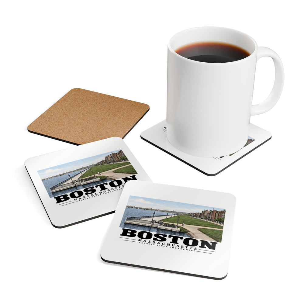 Coasters showing Charles River Embankment riverside path, lawn and buildings artwork beside a plain white mug of coffee and a coaster's cork reverse