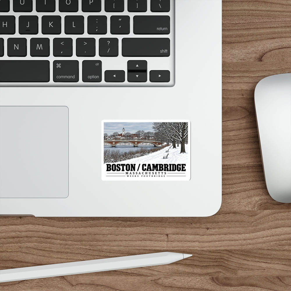 Sticker showing Weeks Footbridge winter riverbank view with snow and benches artwork on a laptop beside its keyboard