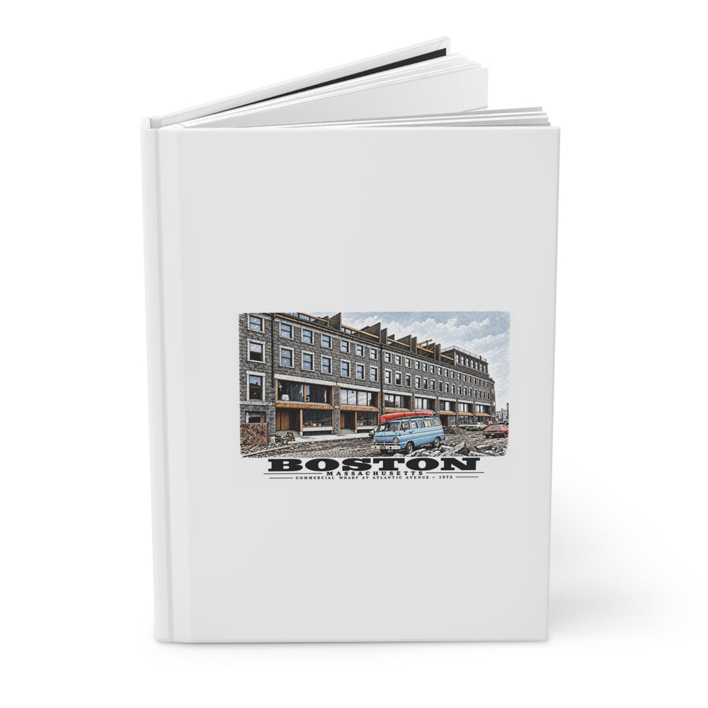 Partly opened white hardcover journal showing Commercial Wharf Street buildings, blue van and renovation debris artwork on the front