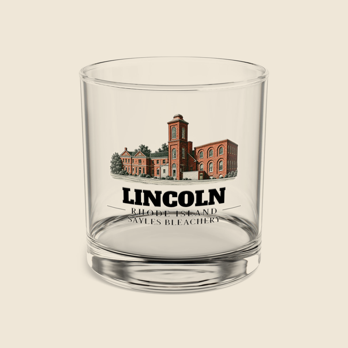 Lincoln Sayles Bleachery rocks glass with colored engraving, shown on a cream background