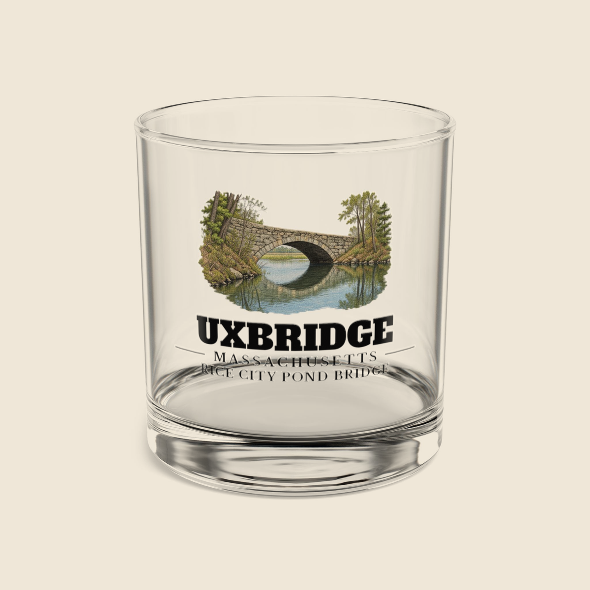 Uxbridge Rice City Pond Bridge rocks glass with colored engraving, shown on a cream background